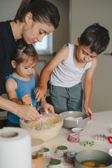 Little son helping mother to kneading dough with flour at home, cooking cookies or cake together, sitting at table in kitchen. Baking cooking preparing surprise