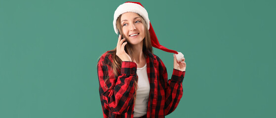 Sticker - Happy young woman in Santa hat talking by mobile phone on green background