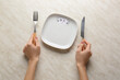 © Pixel-Shot - Female hands with empty plate and cutlery on light background. Diet concept