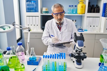 Wall Mural - Senior grey-haired man scientist writing report working at laboratory