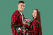 © Pixel-Shot - Young couple in pajamas with Christmas gifts on green background