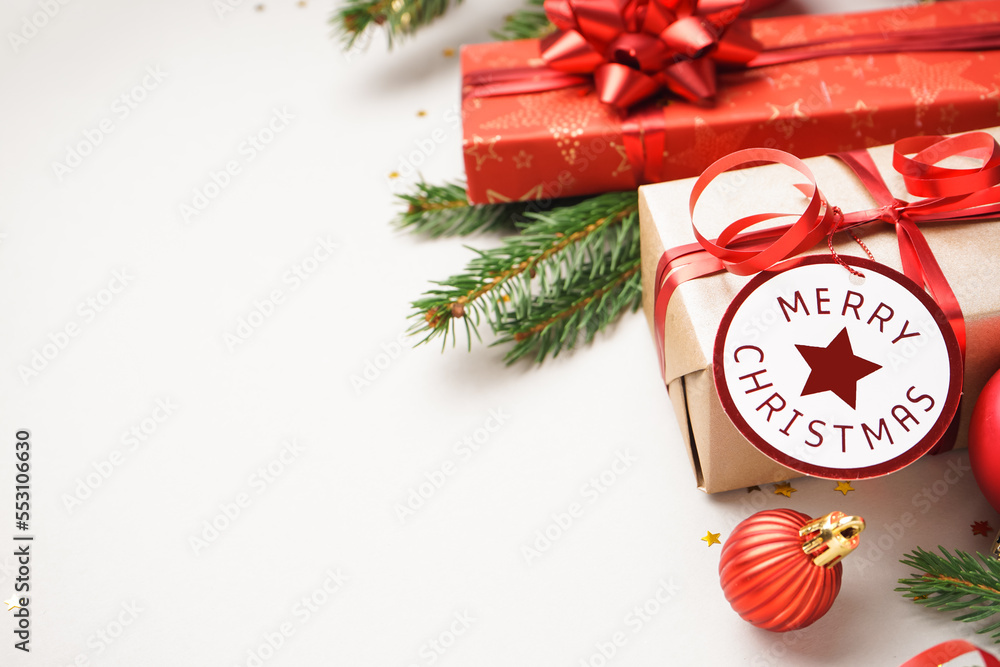 Gift boxes with Christmas ball and fir branches on white background, closeup