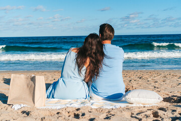 Wall Mural - Young couple in love on the beach summer vacation. Happy man and woman look at the sea 