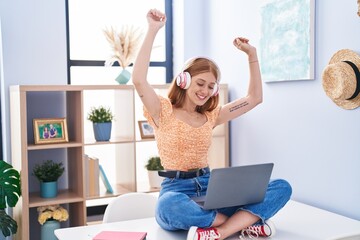 Sticker - Young redhead woman listening to music sitting on table at home