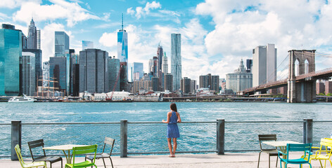 Wall Mural - New York city Manhattan skyline seen from Brooklyn waterfront - woman looking at view. American people walking enjoying view of Manhattan over the Hudson river from the Brooklyn side. NYC cityscape