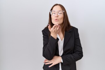 Canvas Print - Beautiful brunette woman wearing business jacket and glasses looking at the camera blowing a kiss with hand on air being lovely and sexy. love expression.