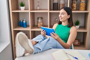 Poster - Young hispanic woman using touchpad sitting on table at home