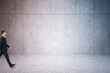 © Who is Danny - Businessman walking in modern concrete tile underground passage with mock up place on wall.