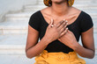 © Westend61 - Woman with hands on chest sitting at staircase