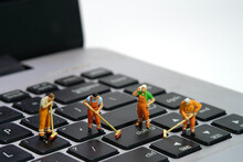 Miniature People Toy Figure Photography. Group Of Sweeper Workers Cleaning Notebook Laptop Keyboard Using Broom, Brush. Isolated On White Background