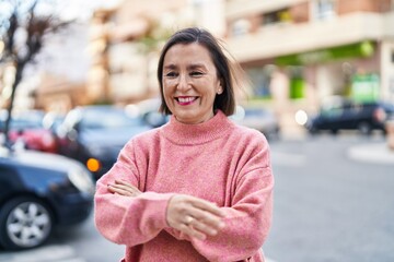 Wall Mural - Middle age woman smiling confident standing with arms crossed gesture at street