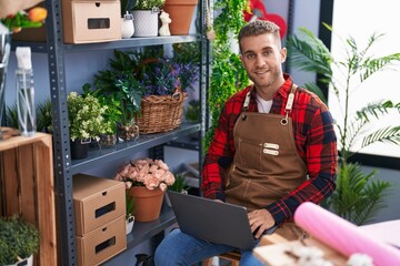 Wall Mural - Young caucasian man florist smiling confident using laptop at flower shop