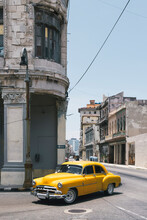 Cuba, Havana, Yellow Vintage Car Driving Along Street In Centro Habana