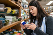 © PR Image Factory - closeup of Asian woman customer holding tiny blue ceramic bowl carefully while looking at it inside shop selling kitchen tableware on Doguyasuji Shopping Street in Osaka japan