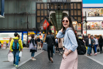 Canvas Print - happy fashionable Asian female tourist wearing sunglasses turning to smile at camera near shinsaibashisuji station shopping district in Osaka japan