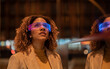 © Westend61 - Young woman with curly hair wearing blue and pink smart glasses at night