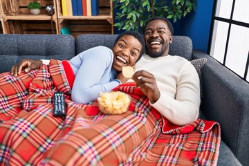 Poster - Young african american couple sitting on the sofa watching tv celebrating crazy and amazed for success with open eyes screaming excited.