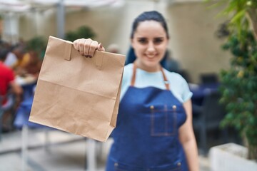 Wall Mural - Young caucasian woman waitress smiling confident holding take away food at coffee shop terrace