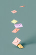 © Westend61 - Three dimensional render of pastel colored envelopes falling down against green background