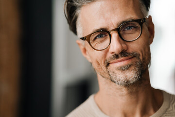 Closeup of middle-aged man smiling at camera while standing indoors