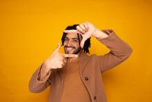 Smiling Man Making Finger Frame Against Yellow Background