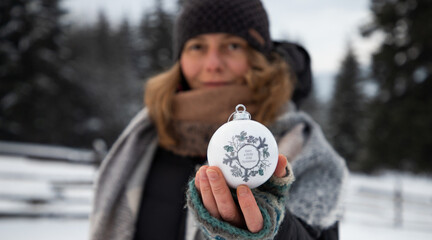 Sticker - woman holding Christmas decoration in snow