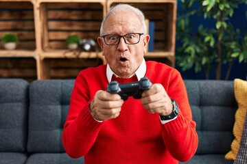 Poster - Senior man playing video game sitting on sofa at home