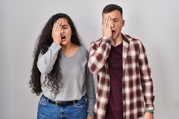 Poster - Young hispanic couple standing over white background yawning tired covering half face, eye and mouth with hand. face hurts in pain.