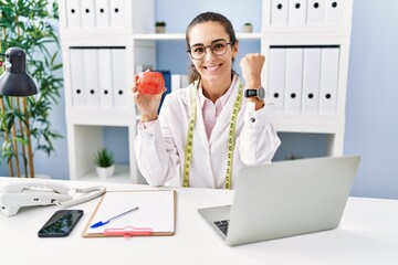 Sticker - Young hispanic woman working dietitian clinic screaming proud, celebrating victory and success very excited with raised arms