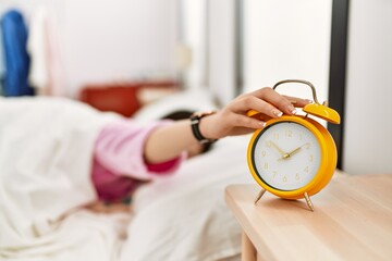 Canvas Print - Girl turning off alarm clock lying on the bed at bedroom.