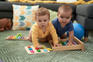 Sticker - Two toddlers playing with maths toys sitting on floor at home