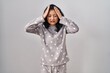 Young asian woman wearing pajama suffering from headache desperate and stressed because pain and migraine. hands on head.