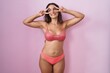 © Krakenimages.com - Young hispanic woman wearing lingerie over pink background doing peace symbol with fingers over face, smiling cheerful showing victory