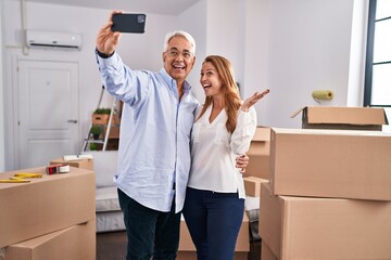 Poster - Middle age man and woman couple make selfie by the smartphone at new home