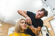 © PoppyPix - Low angle shot of a male hairdresser styling long blonde hair of a woman. High quality photo