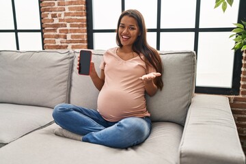 Canvas Print - Young pregnant woman holding smartphone showing screen celebrating achievement with happy smile and winner expression with raised hand