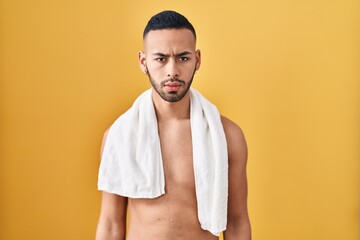 Canvas Print - Young hispanic man standing shirtless with towel skeptic and nervous, frowning upset because of problem. negative person.