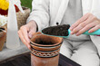 Woman adding fresh soil into pot in garden, closeup