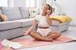 © Krakenimages.com - Young beautiful hispanic woman listening to music doing yoga exercise at home