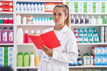 Poster - Young blonde woman working at pharmacy drugstore holding notebook skeptic and nervous, frowning upset because of problem. negative person.