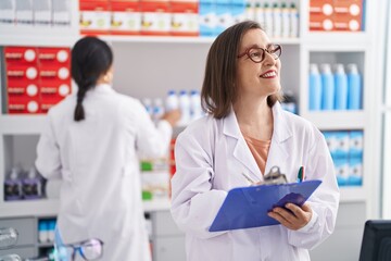 Poster - Two women pharmacist smiling confident writing on document at pharmacy