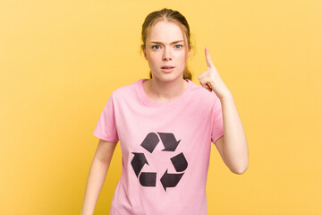 Young caucasian woman wearing a recycling t-shirt isolated on yellow background having an idea, inspiration concept.