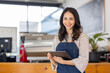© David - Portrait young Asian woman barista feeling happy smiling at urban cafe. Small business owner Asian girl in apron at small business entrance.