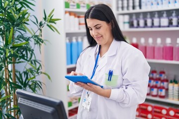 Canvas Print - Young beautiful hispanic woman pharmacist using touchpad working at pharmacy