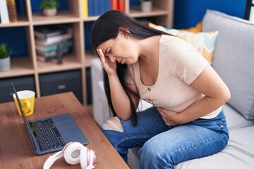 Wall Mural - Young beautiful hispanic woman suffering for head and stomach ache at home