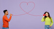 © ViDi Studio - Young couple two friends family man woman of African American ethnicity wear casual clothes together talk speak by cups phone with thread heart shape isolated on pastel plain light purple background.