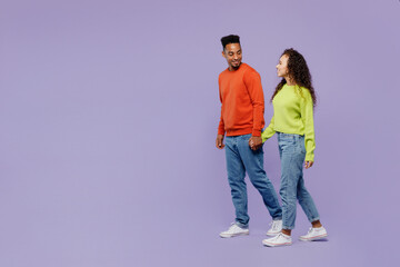 Sticker - Full body side view young couple two friends family man woman of African American ethnicity wear casual clothes hold hands walk go strolling together isolated on pastel plain light purple background.