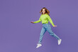 © ViDi Studio - Full body side view fun young woman 30s she wearing casual green knitted sweater walking going jump high pov fly isolated on plain pastel purple background studio portrait. People lifestyle concept.