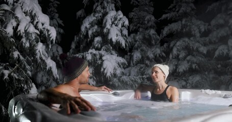 Wall Mural - couple relaxing in outdoor hot tub at spa resort in winter