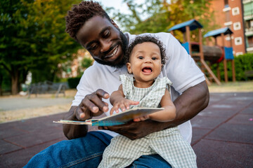 Young man and a little girl reading a book together and looking involved